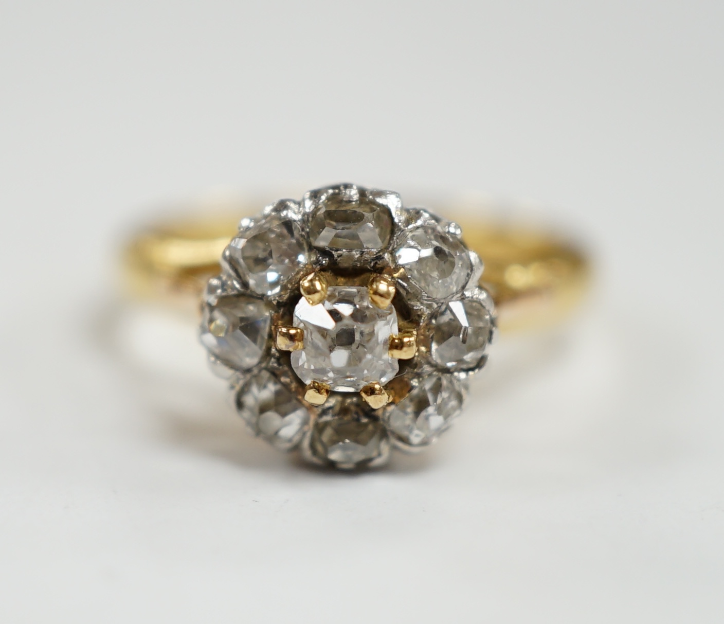 An early 20th century French 18k and nine stone diamond set flower head cluster ring, size G, gross weight 3.4 grams.